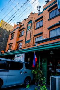 ダバオシティにあるTINHAT Halal حلال Certified Boutique Hotel And Restaurantの旗を掲げた建物前に停車するバン
