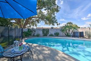 a swimming pool with a table and an umbrella at Scottsdale Home with Pool, Yard, Hammock and Fire Pit! in Scottsdale