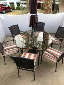 a glass table with chairs and an umbrella on a patio at El Viejo Adobe - Across from Sul Ross campus in Alpine