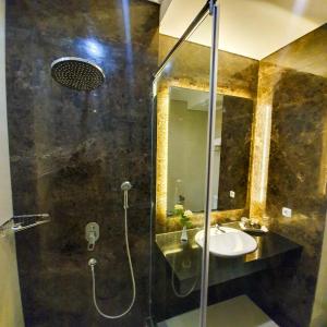 a bathroom with a shower with a sink and a mirror at Sutanraja Hotel & Convention Centre in Soreang