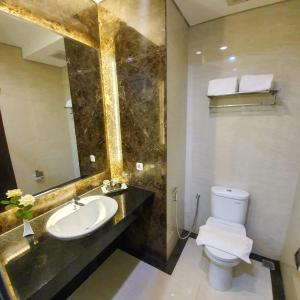 a bathroom with a sink and a toilet and a mirror at Sutanraja Hotel & Convention Centre in Soreang