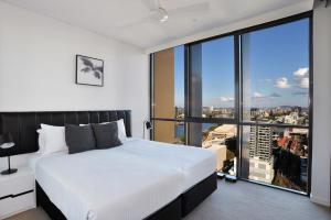 a bedroom with a white bed and a large window at Hope Street Apartments by CLLIX in Brisbane