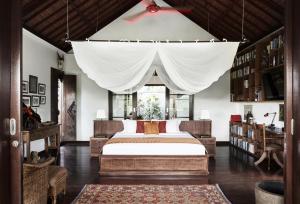 a bedroom with a bed with a white canopy at Villa Bayad in Payangan