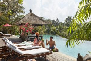 a group of people sitting by the pool at a resort at Villa Bayad in Payangan