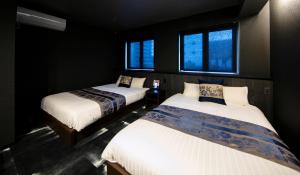 two beds in a room with two windows at GRAND BASE Takamatsu in Takamatsu