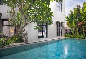 a swimming pool in front of a house with trees at The Aswana Seminyak in Seminyak