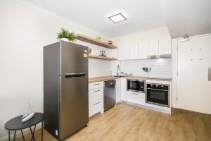 a kitchen with a stainless steel refrigerator and a table at ALEXANDRA BEACH RESORT-ALEX412 in Alexandra Headland
