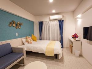 宮古島にあるかりゆしコンドミニアムリゾート宮古島 ふくぎステイズのベッドとソファ付きのホテルルーム