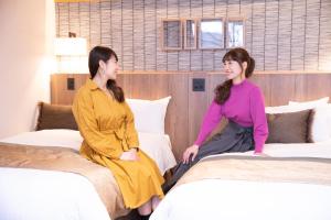 two women sitting on beds in a hotel room at Minakami Hotel Juraku in Minakami
