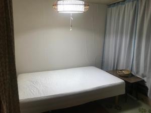 a small room with a white bed and a light at Otaru stay in Otaru