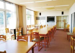 Sala de conferencias con mesas, sillas y TV en 海のお宿, en Susami