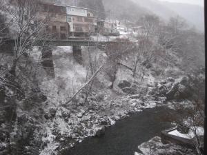 un pont sur une rivière recouverte de neige dans l'établissement Minakami Hotel Juraku, à Minakami