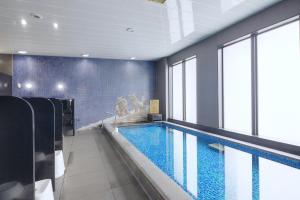 a swimming pool in a building with a large window at Almont Hotel Naha Kenchomae in Naha