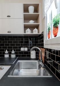 a kitchen with a sink and a black tiled wall at Absolute Athens XI in Athens