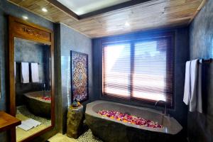 a bathroom with a large tub with a window at Kenran Resort Ubud By Soscomma in Ubud