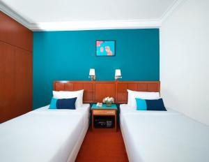 2 camas en una habitación con paredes azules en JO Hotel Johor Bahru en Johor Bahru