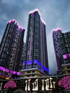 three tall buildings with purple lights on them at I City Residence, 2 Bedroom 4-6 Pax unit, Walking to Theme n Water Park & Shopping Mall in Shah Alam