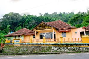 una casa gialla sul lato di una strada di OYO Life 2638 Hotel Raya a Sarangan