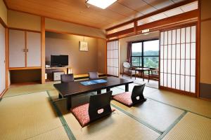 Zimmer mit einem Tisch, Stühlen und einem TV in der Unterkunft Yunogo Bishunkaku in Mimasaka