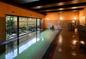 a swimming pool in a building with a large window at HOTEL ROUTE-INN Kamiyamada Onsen in Chikuma