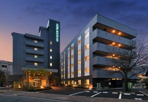wysoki budynek z parkingiem przed nim w obiekcie HOTEL ROUTE-INN Kamiyamada Onsen w mieście Chikuma