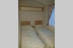 黑潭的住宿－Stunning deluxe 3 bedroomed caravan with CH, DG and decking.，一间位于角落的卧室,配有两张床