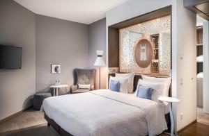 a bedroom with a large bed and a chair at Steigenberger Hotel München in Munich