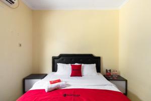 1 dormitorio con 1 cama grande con almohadas rojas en RedDoorz @ Raya Janti Yogyakarta, en Yogyakarta