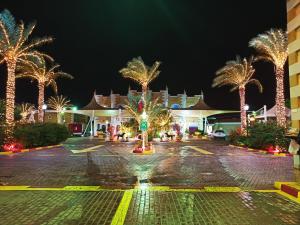 um parque de estacionamento com palmeiras iluminadas à noite em Tio Sea Resort em Al Khor