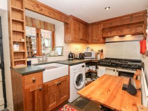 a kitchen with wooden cabinets and a white dishwasher at Middle Cottage in Stoke on Trent