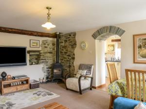 a living room with a fireplace and a tv at Mimi's Cottage in Liskeard