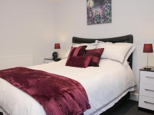 a bedroom with a white bed with red pillows at Alders View Coach House in Craven Arms