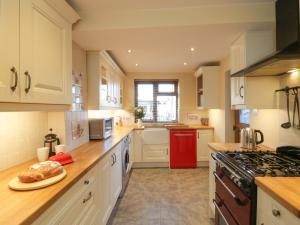 uma cozinha com armários brancos e um frigorífico vermelho em Eskside Cottage em Whitby