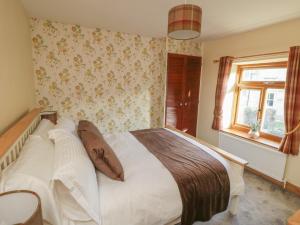 um quarto com uma grande cama branca e uma janela em Eskside Cottage em Whitby