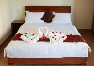 een bed met twee witte handdoeken en rozen erop bij Khách sạn Trường Long in Phan Rang