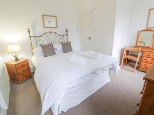 a bedroom with a large white bed and a dresser at Turret Cottage in Prestonpans