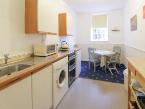 une cuisine avec un lave-linge, un sèche-linge et une table dans l'établissement Turret Cottage, à Prestonpans