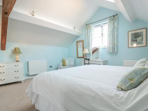 - une chambre bleue avec un lit blanc et une fenêtre dans l'établissement The Hayloft, à Bromyard