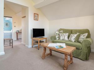 a living room with a green couch and a coffee table at The Hayloft in Bromyard