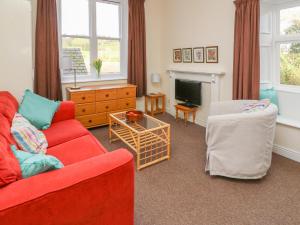 a living room with a red couch and a tv at Garden View in Kington