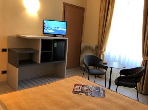 um quarto com uma televisão, uma mesa e cadeiras em Hotel Tirrenia em Viareggio