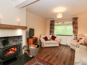 een woonkamer met een bank en een open haard bij Glenfinglas Dam Cottage in Callander