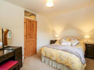 een slaapkamer met een bed, een dressoir en een spiegel bij Glenfinglas Dam Cottage in Callander