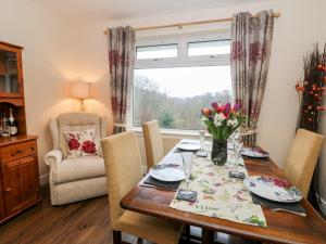 een eetkamer met een tafel en stoelen en een raam bij Glenfinglas Dam Cottage in Callander