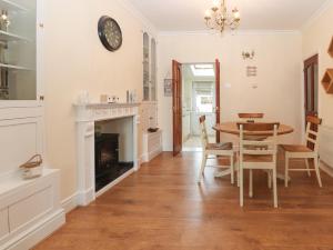 a dining room with a table and a fireplace at Park View Cottage in Mold