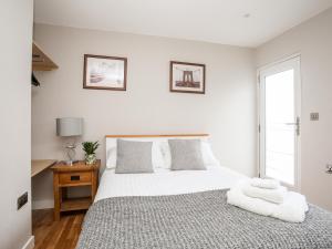 a bedroom with a bed with white sheets and a window at Laneton in Rhosneigr