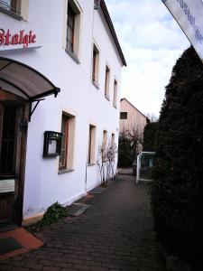 a white building with a brick walkway next to it at Pension & Gasthaus Nostalgie in Chemnitz