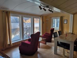 a living room with chairs and a table and windows at Visit Undredal in Undredal