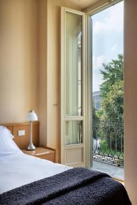 Dynasty Suites Downtown Apartments في تورينو: غرفة نوم بسرير وباب زجاجي منزلق