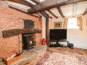 a living room with a brick fireplace and a tv at Chapel Cottage in Tarporley